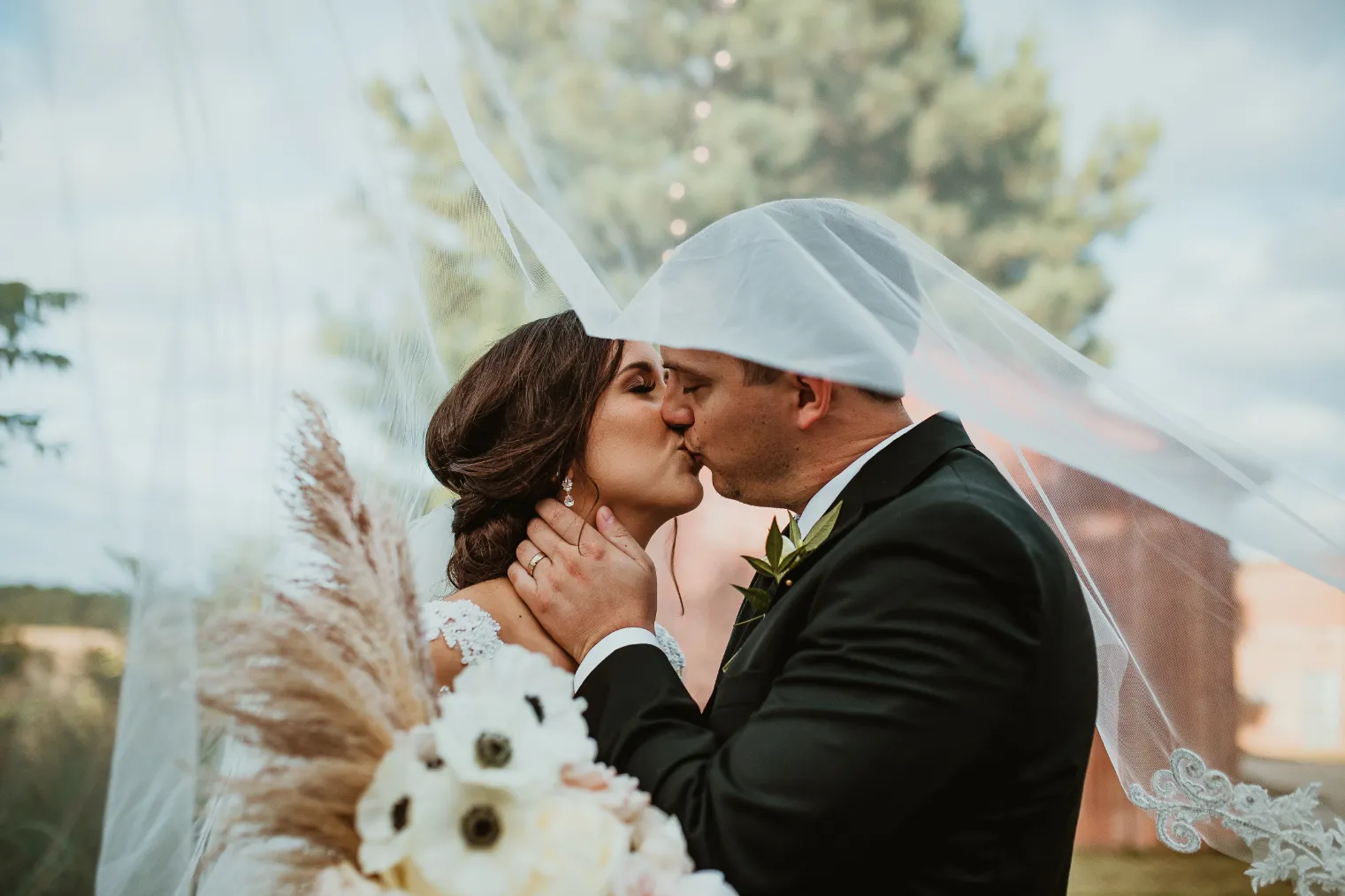 Bride and groom kissing underneath a veil at Empire Mills in Madison, Georgia