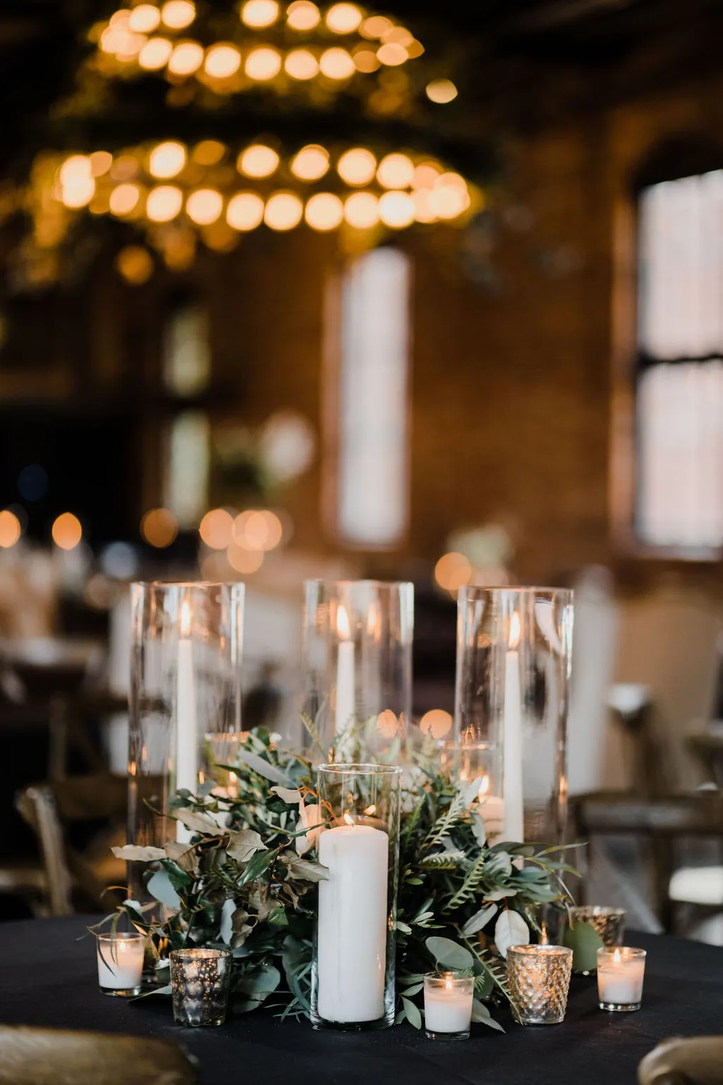 Lit candles and greenery as a classic wedding table centerpiece