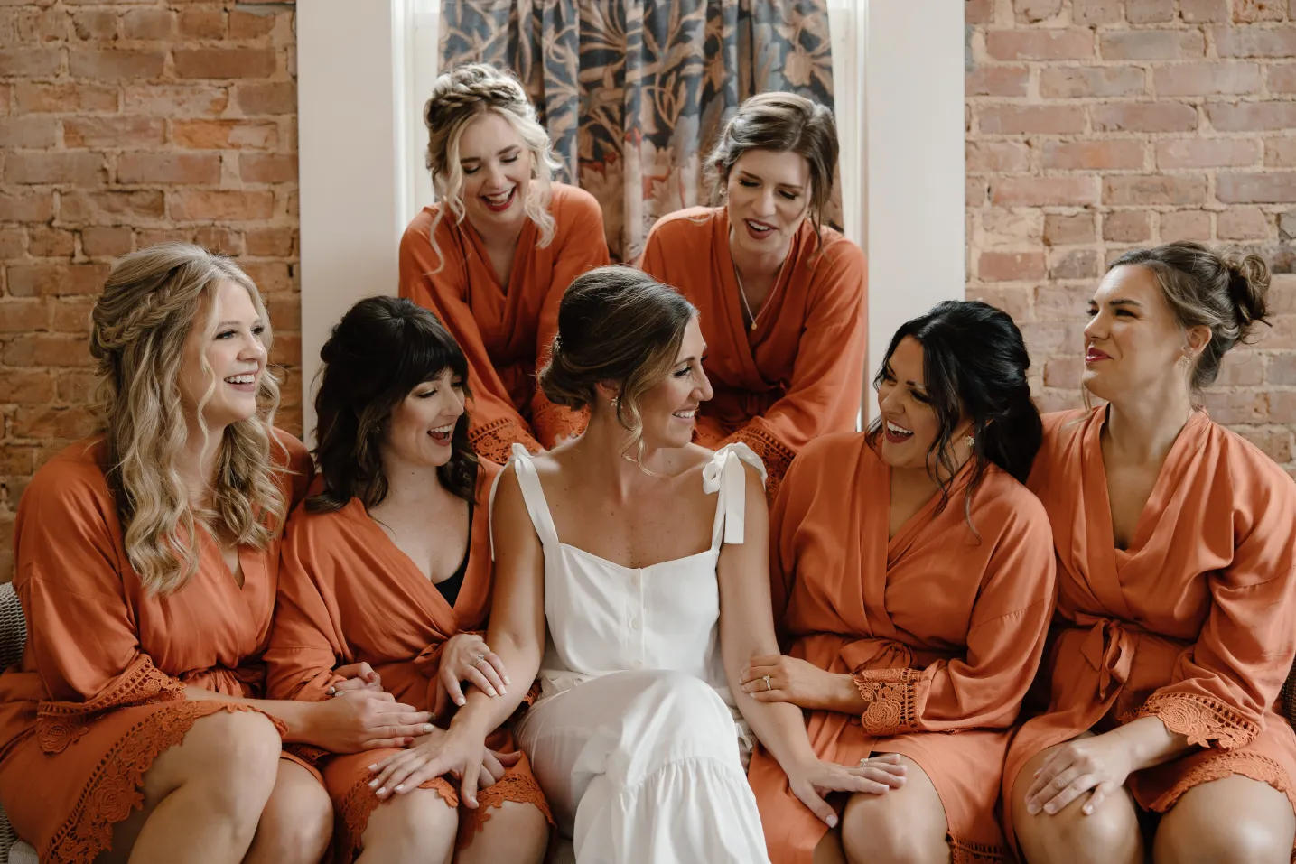 Bride and bridesmaids getting ready for a wedding smiling and laughing together at Empire Mills in Madison, Georgia