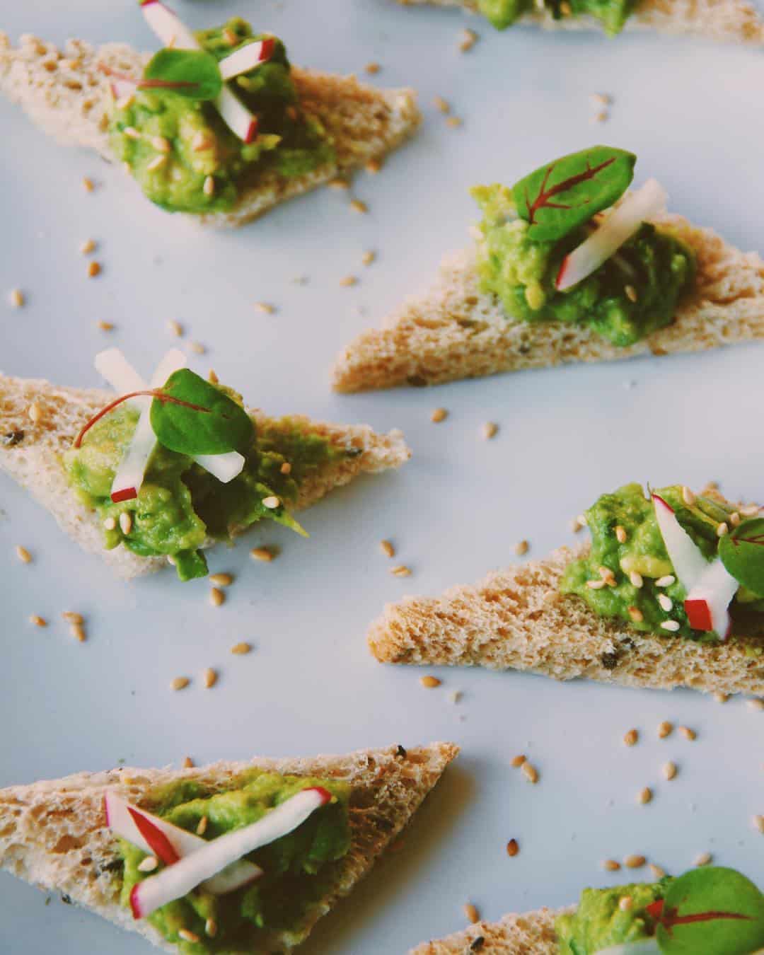 Mini bread appetizers with avocado and other fresh garnishes