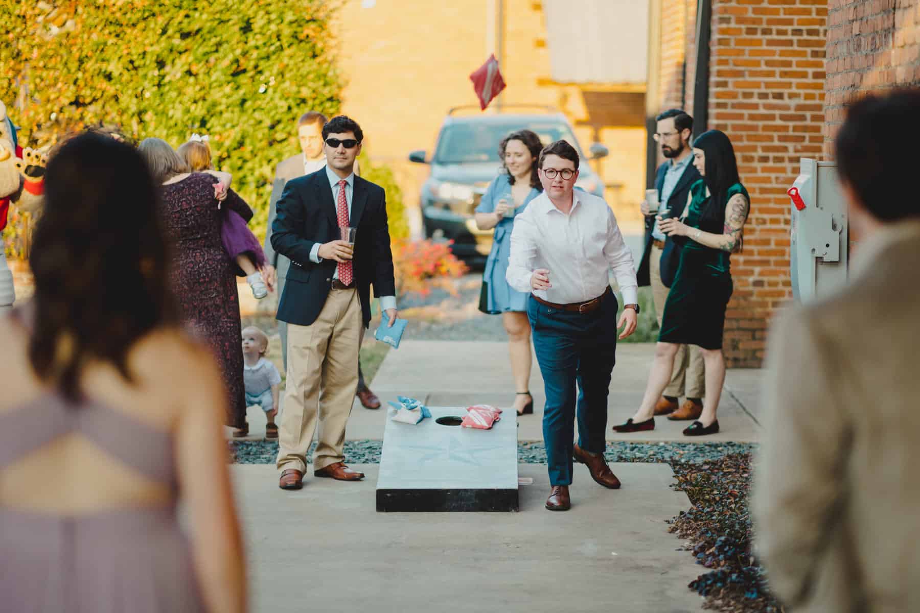 Men playing corn hole outside enjoying themselves at an event at Empire Mills in Madison, Georgia.