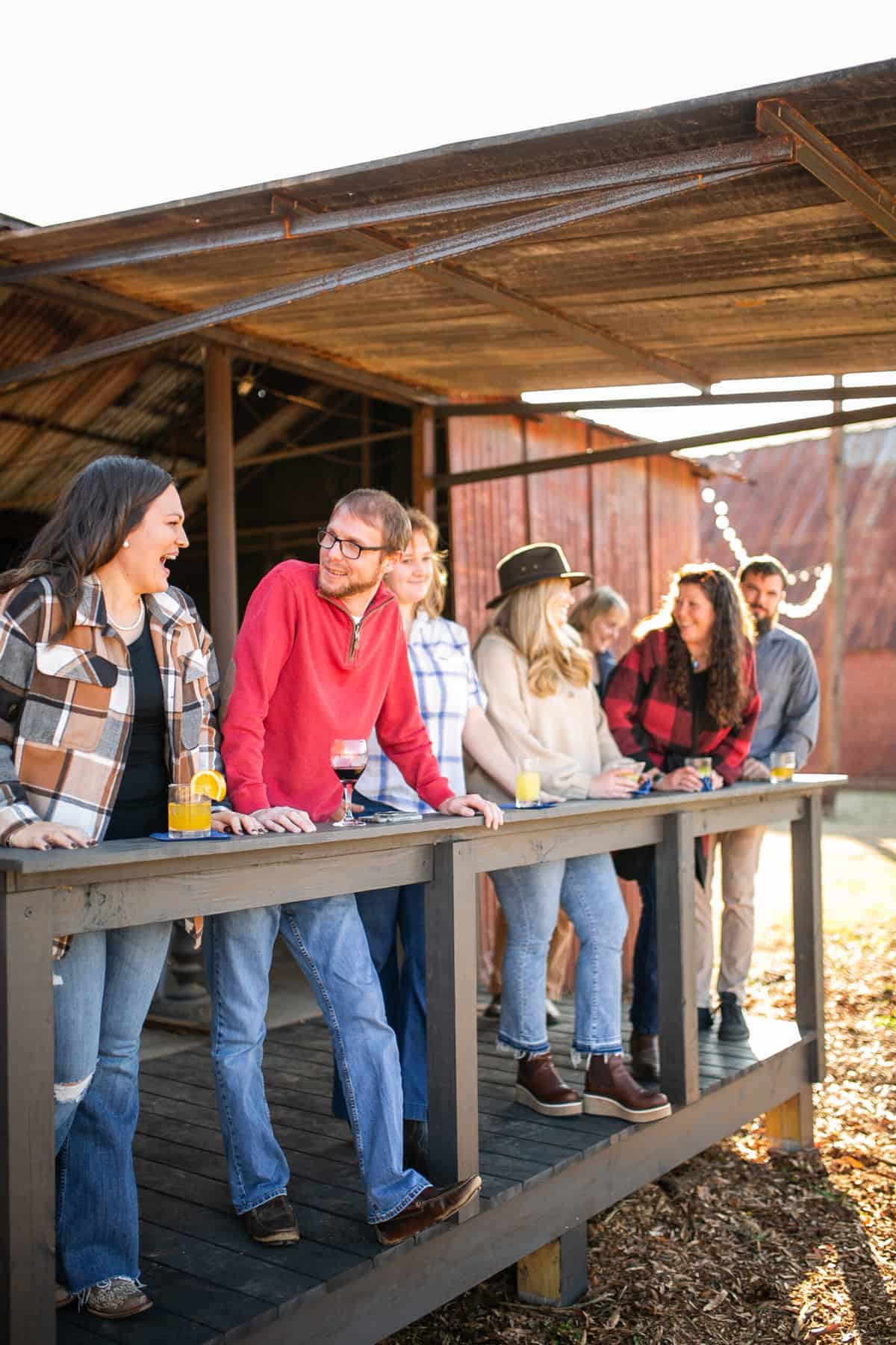 A group of people smiling and laughing and enjoying drinks together at an outdoor social event at Empire Mills in Madison, Georgia.