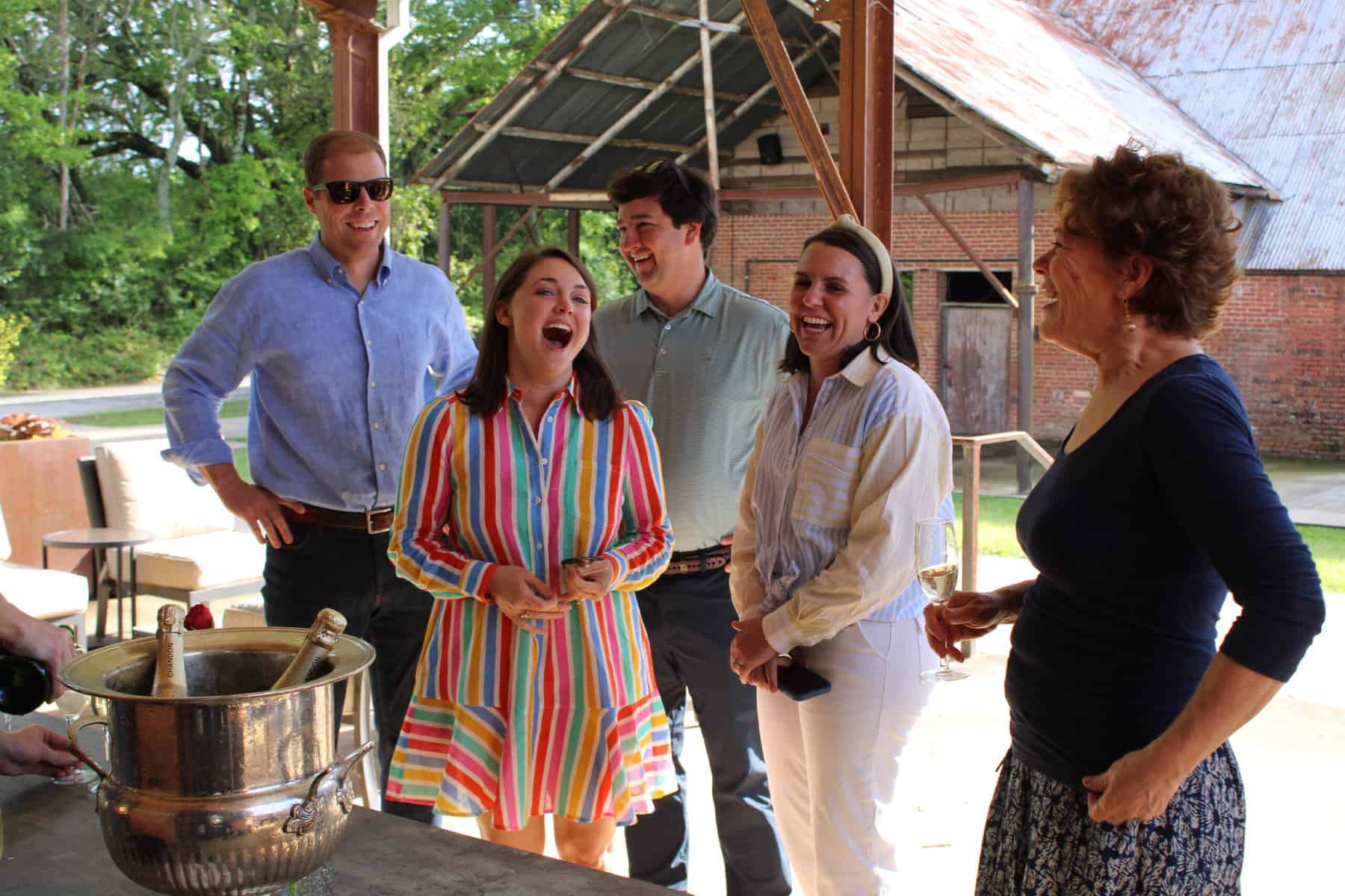 Happy people in small-town Georgia enjoying an outdoor social event at Empire Mills on a sunny day drinking champagne 