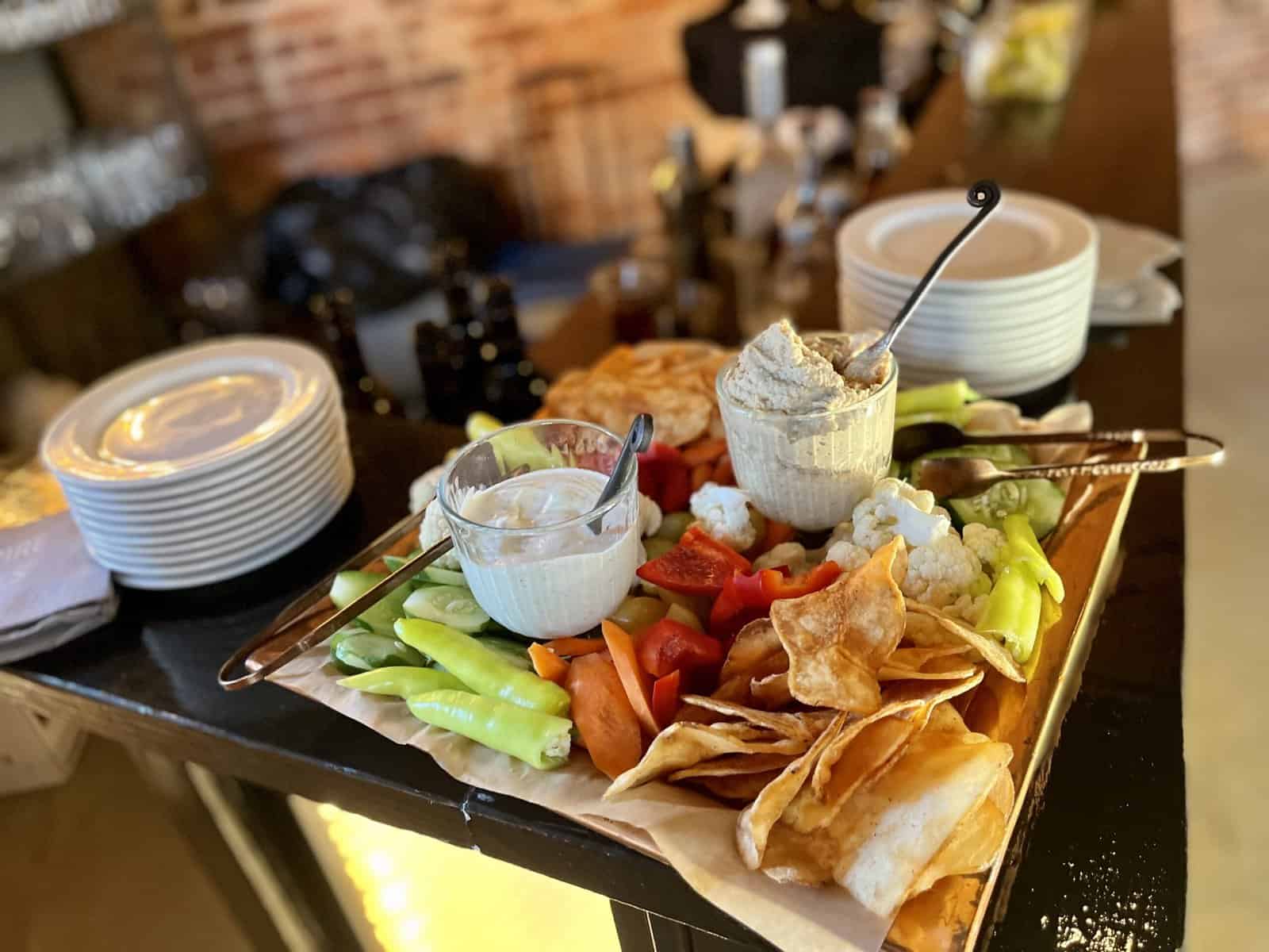 A fresh spread of various vegetables, chips, and dips.