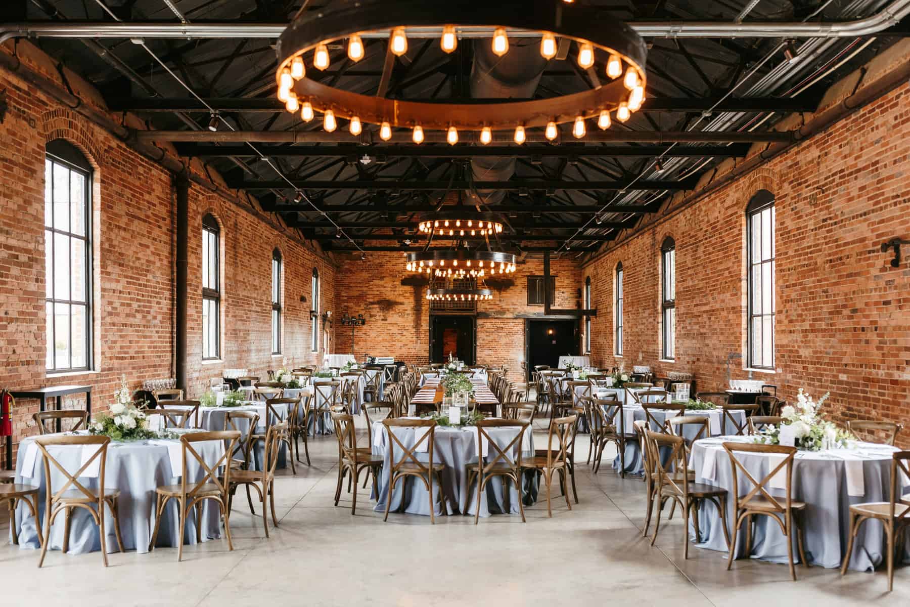 Grande hall set up for wedding reception with tables, florals, and linens at Empire Mills in Madison, Georgia.