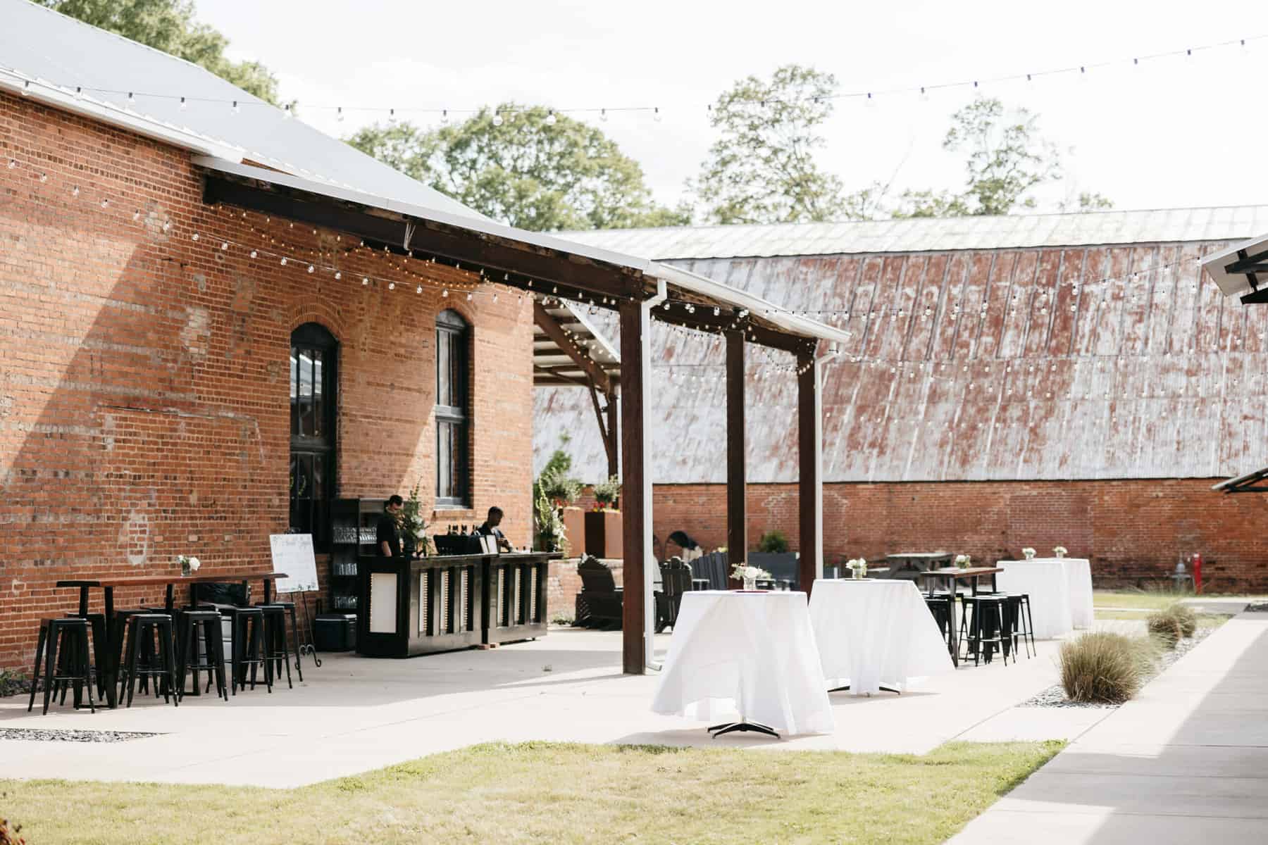 Interior courtyard set up for wedding with tables and bar in a rustic elegant setting at Empire Mills in Madison, Georgia.